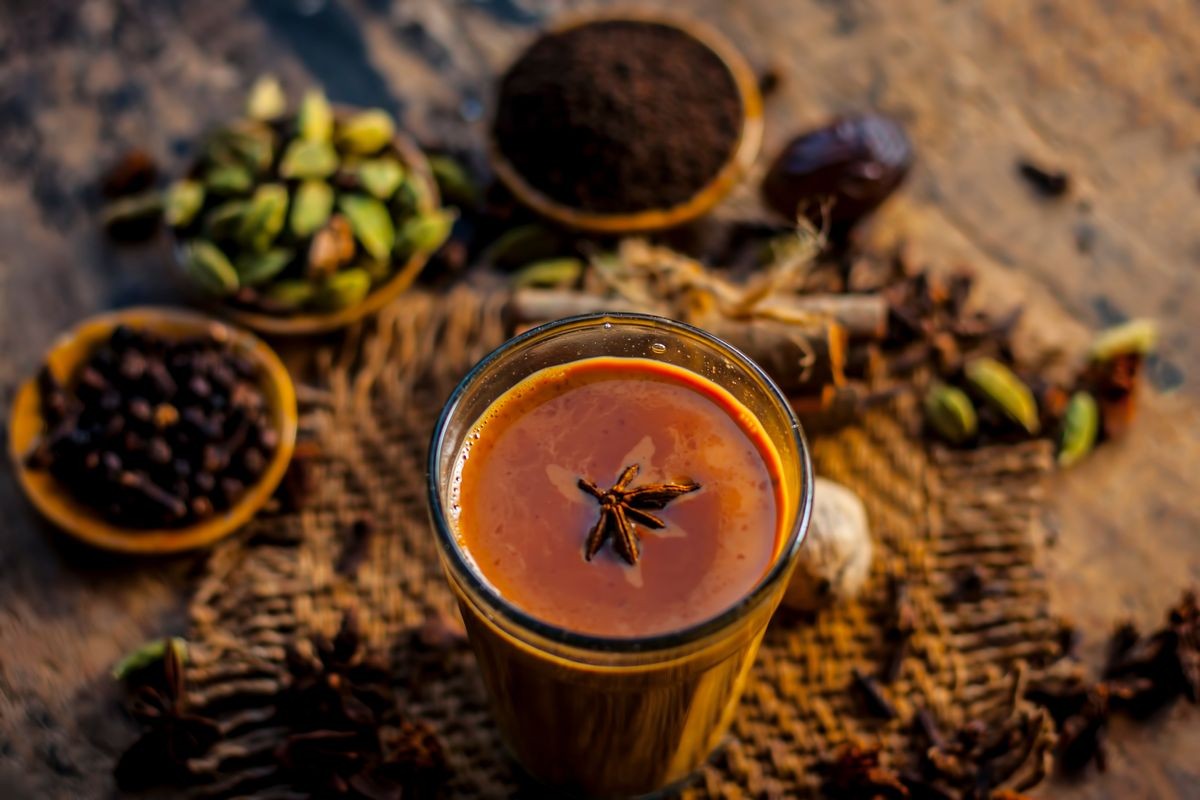 Close up of popular Indian/Asian drink " 
Masala Chai" or Spicy tea/normal tea with all the ingredients including sugar on a wooden surface.
